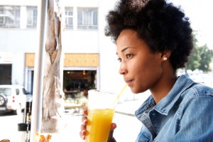 Portrait of fashionable young african woman sipping orange juice